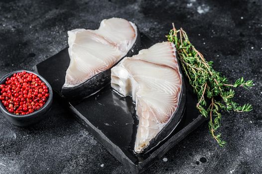 Raw Shark fish steaks on a board. Black background. Top view.