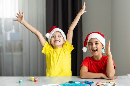 Happy kids making christmas cards wearing santa hats.