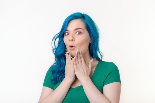 Young beautiful woman with blue hair with facial expression of surprise standing over white background