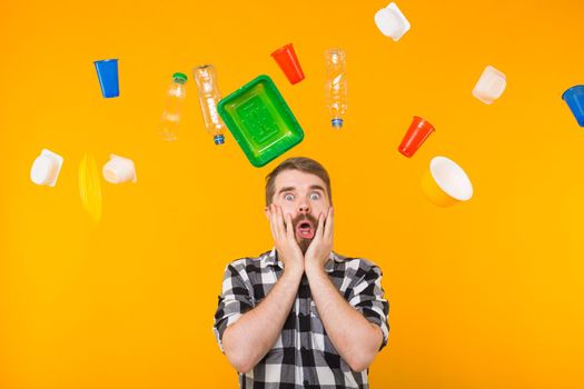 World Environment Day, plastic recycling problem and environmental disaster concept - Terrified man on yellow background with trash.