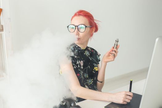 Creative, graphic designer, people concept - young creative woman smoking a vape while working in a graphic tablet.
