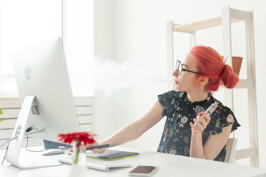 Creative, graphic designer, people concept - young creative woman smoking a vape while working in a graphic tablet.