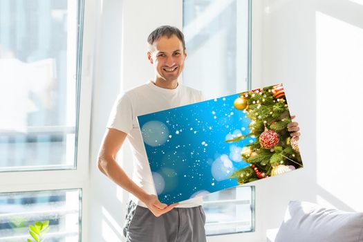 a man holding a photo canvas with a picture of christmas.