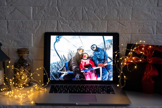 Image of open laptop family and christmas on wooden table in front of christmas tree background.