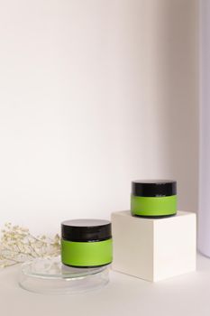 Focus on little two jars of facial cosmetic cream with green space for brand in background with copy space. Concept of cluelty free, organic, kosher cream is great for dry and rough skin.