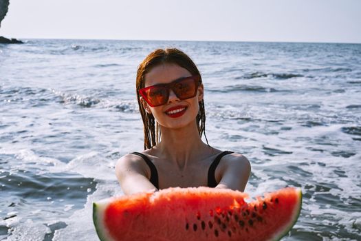 pretty woman in a black swimsuit with a watermelon in her hands summer Ocean. High quality photo