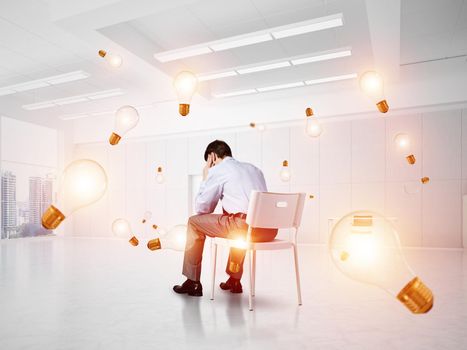 young businessman sitting on a chair with his head in his hands