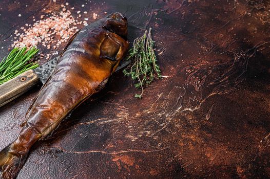 Hot smoked fish walleye or pike perch on a wooden board with herbs. Dark background. Top view. Copy space.