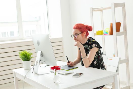 Illustrator, graphic designer, animator and artist concept - creator woman with beautiful red hair and glasses drawing in laptop.