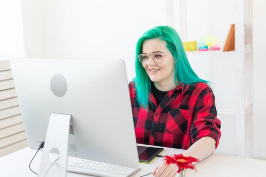 Graphic designer, animator and illustrator concept - young woman with green hair working at the laptop.