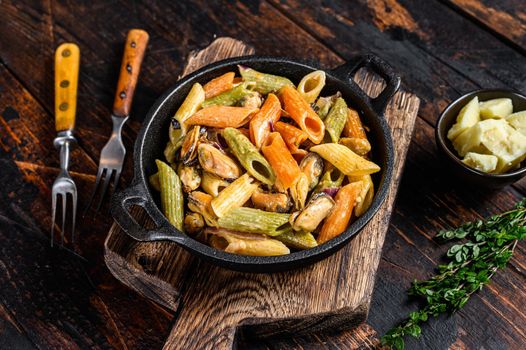 Penne pasta in cream sauce with seafood. Dark Wooden background. Top view.