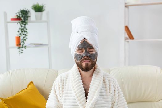 Bearded man has clean fresh skin, wears beauty clay mask on face and enjoys beauty treatments. Spa at home, body and skin care.
