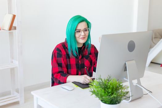 Business, designer and animator concept - young woman illustrator or artist with green hair draws on the graphic tablet.