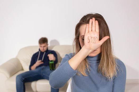 People, domestic violence and abuse concept - Woman shows stop abusing sign over man's background.