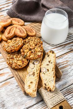 Closeup of a group of assorted cookies with glass of milk. White wooden background. Top view.