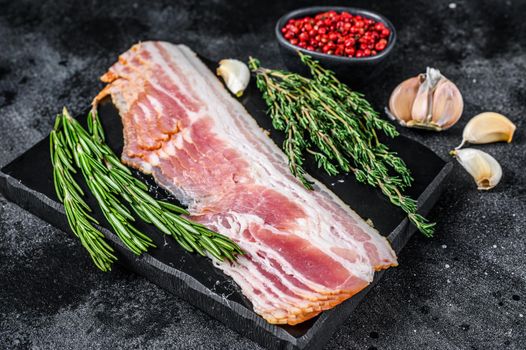 Raw sliced pork bacon ready for cooking. Black background. Top view.