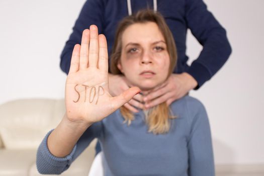 People, domestic violence and abuse concept - Woman shows stop abusing sign over man's background.