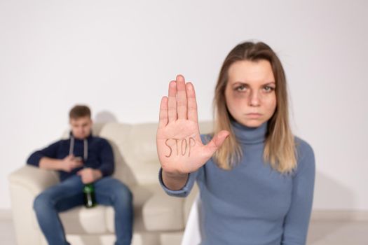 People, domestic violence and abuse concept - Woman shows stop abusing sign over man's background.