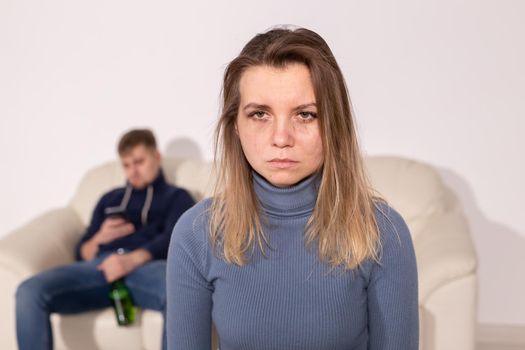 Alcoholism, abuse and domestic violence concept - sad woman with her drunk husband.