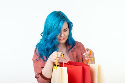 Sale, shopaholic and consumer concept - beautiful girl with blue hair standing with shopping bags on white background.
