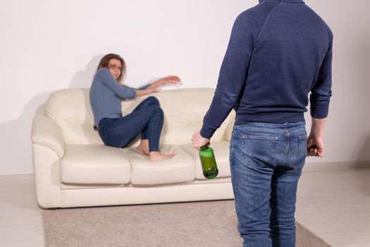 alcoholic, domestic violence and abuse concept - man gets drunk at home and takes his anger at his wife.