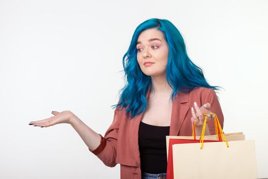 Sale, shopaholic and consumer concept - beautiful girl with blue hair standing with shopping bags on white background.