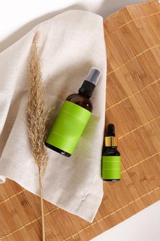 Spray bottles with cosmetic products and green space for your brand on bamboo mat background. Concept of cluelty free, organic, kosher cosmetic online shop and advertisment.