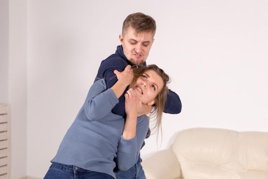 people, abuse and violence concept - agressive man strangling his wife.