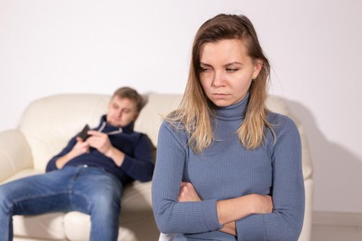 People, domestic violence and abuse concept - Woman with crossed arms and man on the white sofa.