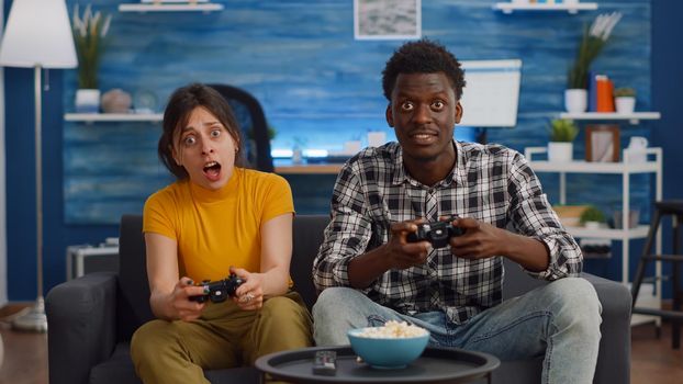 POV of interracial couple playing video game on console in living room. Young multi ethnic people highfive while winning at home. Mixed race partners enjoying fun activity on television