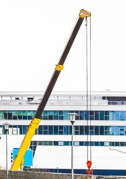 Machine lifting crane industrial equipment at a construction site on the background of a new, modern facade of an urban building.