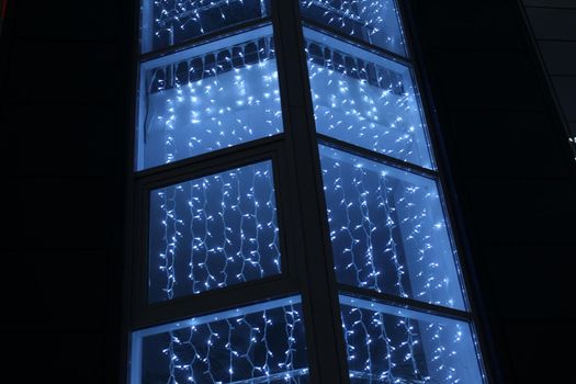 blue blue garlands on a dark black background. New Year's Eve christmas background. Festive lighting.