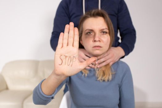 People, domestic violence and abuse concept - Woman shows stop abusing sign over man's background.