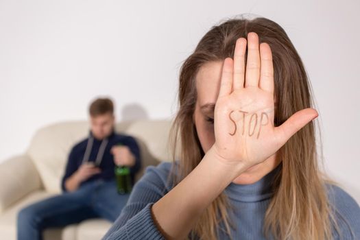 People, domestic violence and abuse concept - Woman shows stop abusing sign over man's background.