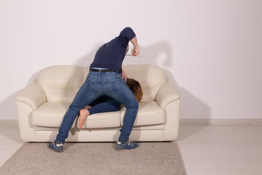 people, abuse and violence concept - aggressive man hitting his wife on sofa.