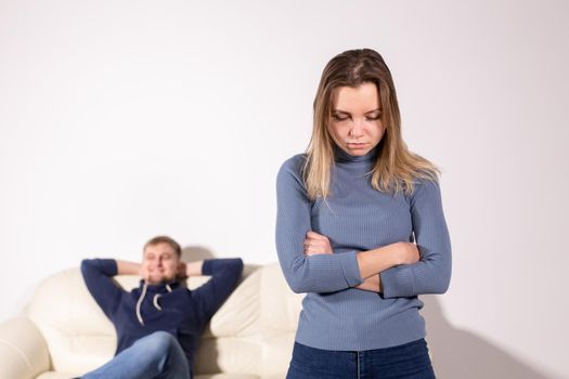 People, domestic violence and abuse concept - Woman with crossed arms and man on the white sofa.