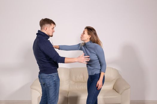 people, violence and abuse concept - angry man hitting woman in her face on sofa.