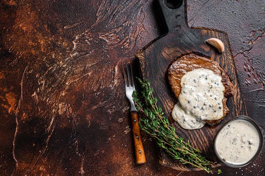 Grilled sirloin beef meat steak with peppercorn sauce. Dark background. Top view. Copy space.