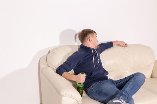 Depression and alcoholism concept - Aggressive male alcoholic sitting on the sofa.