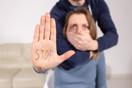 People, domestic violence and abuse concept - Woman shows stop abusing sign over man's background.