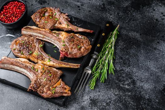 Barbecue fried lamb meat chops on a marble board. Black background. Top view. Copy space.