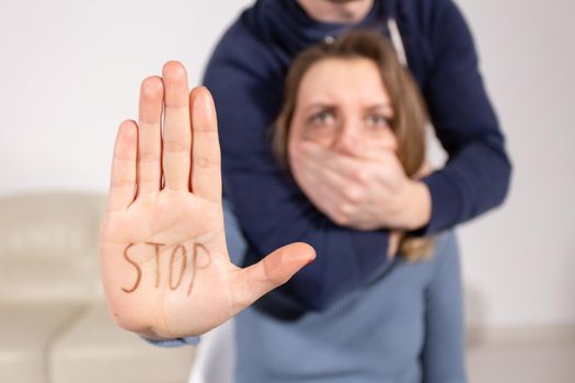 People, domestic violence and abuse concept - Woman shows stop abusing sign over man's background.