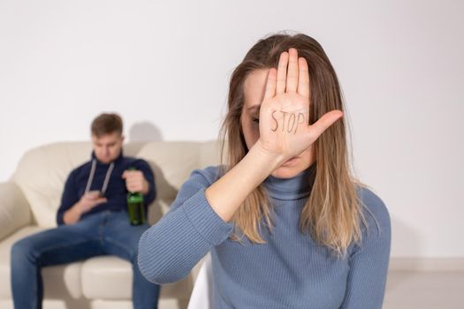 People, domestic violence and abuse concept - Woman shows stop abusing sign over man's background.