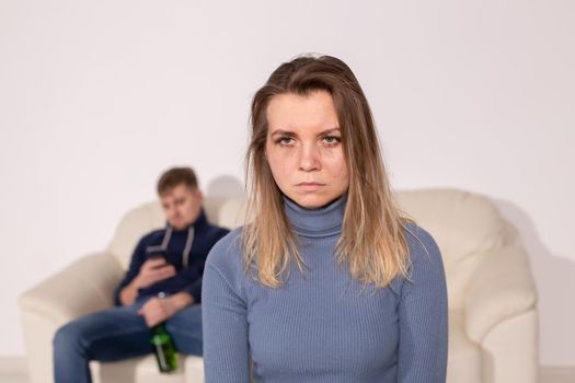 Alcoholism, abuse and domestic violence concept - sad woman with her drunk husband.