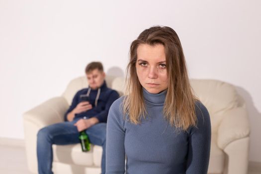 Alcoholism, abuse and domestic violence concept - sad woman with her drunk husband.