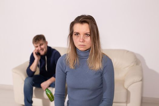 Alcoholism, abuse and domestic violence concept - sad woman with her drunk husband.