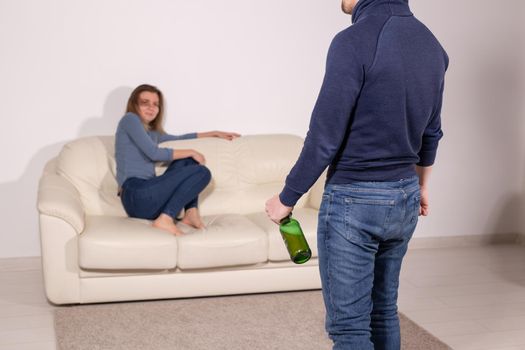 alcoholic, domestic violence and abuse concept - man gets drunk at home and takes his anger at his wife.