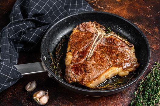 Grilled porterhouse beef meat Steak with herbs in a pan. Dark background. Top view.