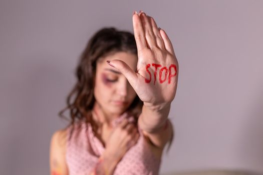 Domestic violence, protesting and people concept - brunette woman expressing denial with STOP on her hand on grey room.