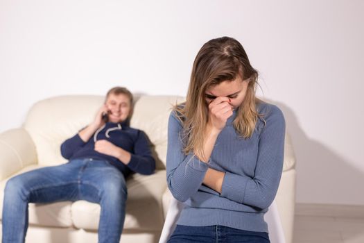 domestic violence, abuse and family concept - crying woman and her husband on the background.